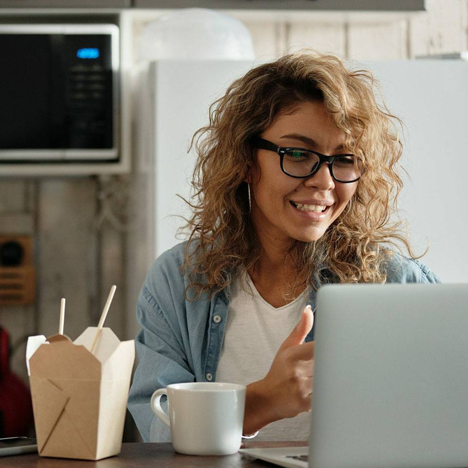 woman sitting with her laptop at her kitchen table, using Match to find a co-buyer